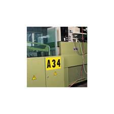 Brady black on yellow outdoor numbers and letters applied to a piece of equipment in a factory.