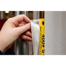Close-up of someone applying a yellow Brady high-performance pipe marker to a pipe.