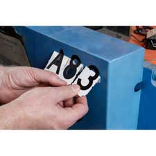 Close-up of person applying three alphanumeric characters reading "A83" to a piece of equipment.
