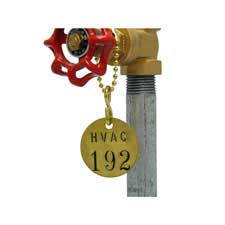 A Brady stamped brass valve tag reading "HVAC  192" hanging from a pipe valve.