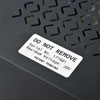 A Brady label reading "Do not remove" with a serial number and maximum voltage applied to a surface.